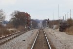 An approaching westbound grain train approaches in the distance as the signals at Smithshire clear the way for an eastbound to cross over in front of it